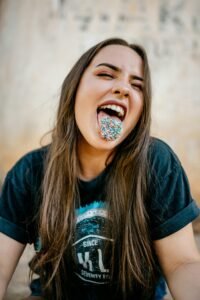 A playful portrait of a woman with rainbow sprinkles on her tongue. Fun and vibrant expression.